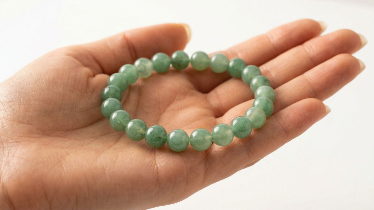 Green aventurine round bead bracelet on palm with Dubai skyline for visa approval - Divine Sansar