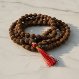 Original 5 Mukhi Rudraksha Mala 108 beads with red tassel on marble - Divine Sansar UAE
