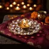 Lit crystal brass diya on maroon silk in a home mandir for Diwali in the UAE - Divine Sansar