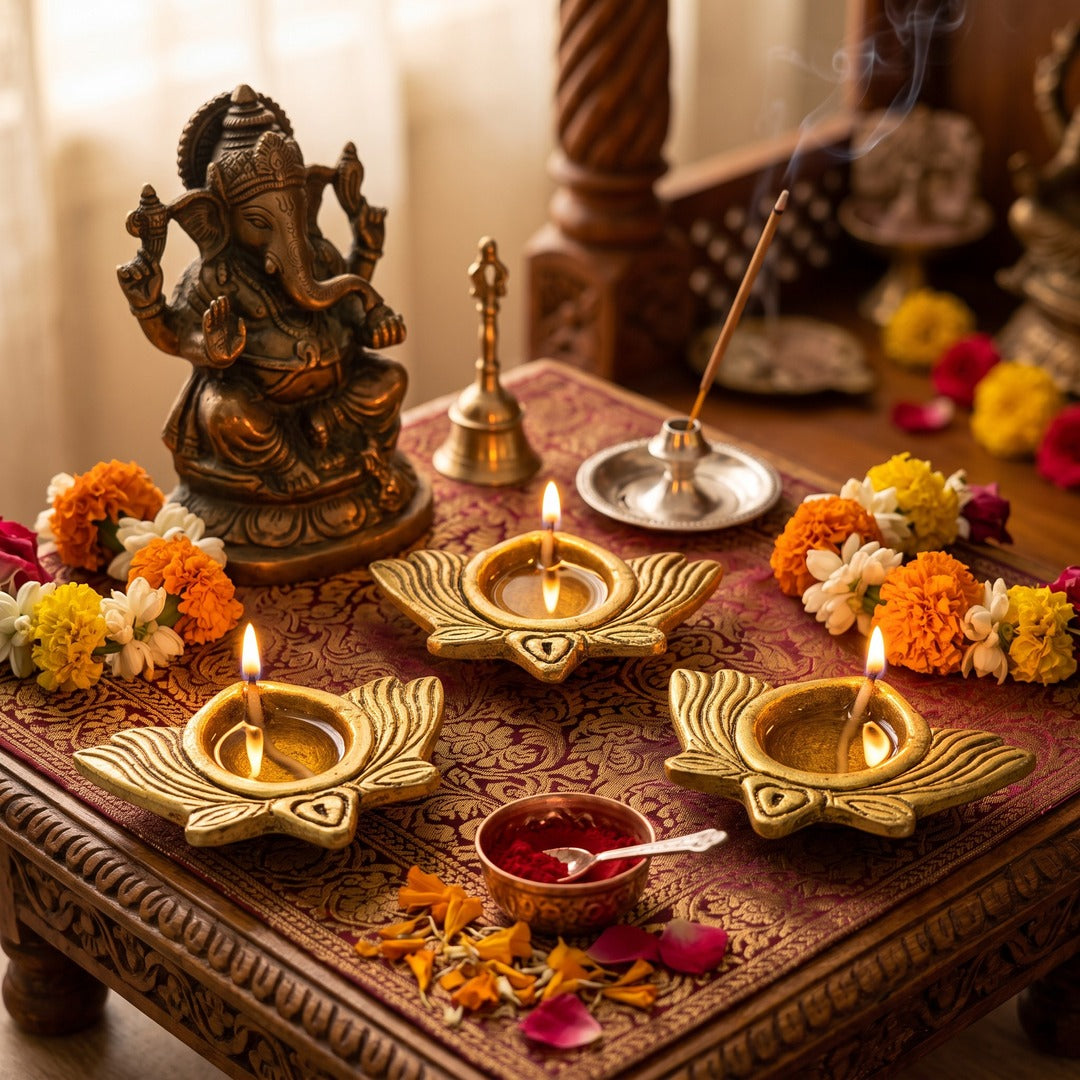 Three lit brass Kamal lotus diyas on a home mandir with Ganesh ji and marigolds - Divine Sansar