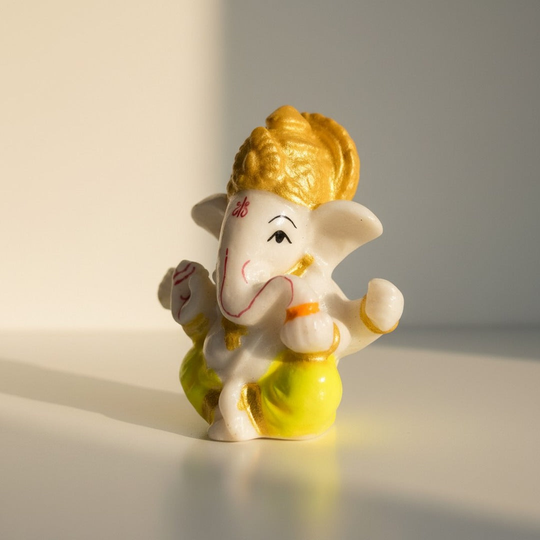 Yellow dhoti Ganesh idol 6 cm shown in natural light on a desk, small Ganesha murti - Divine Sansar