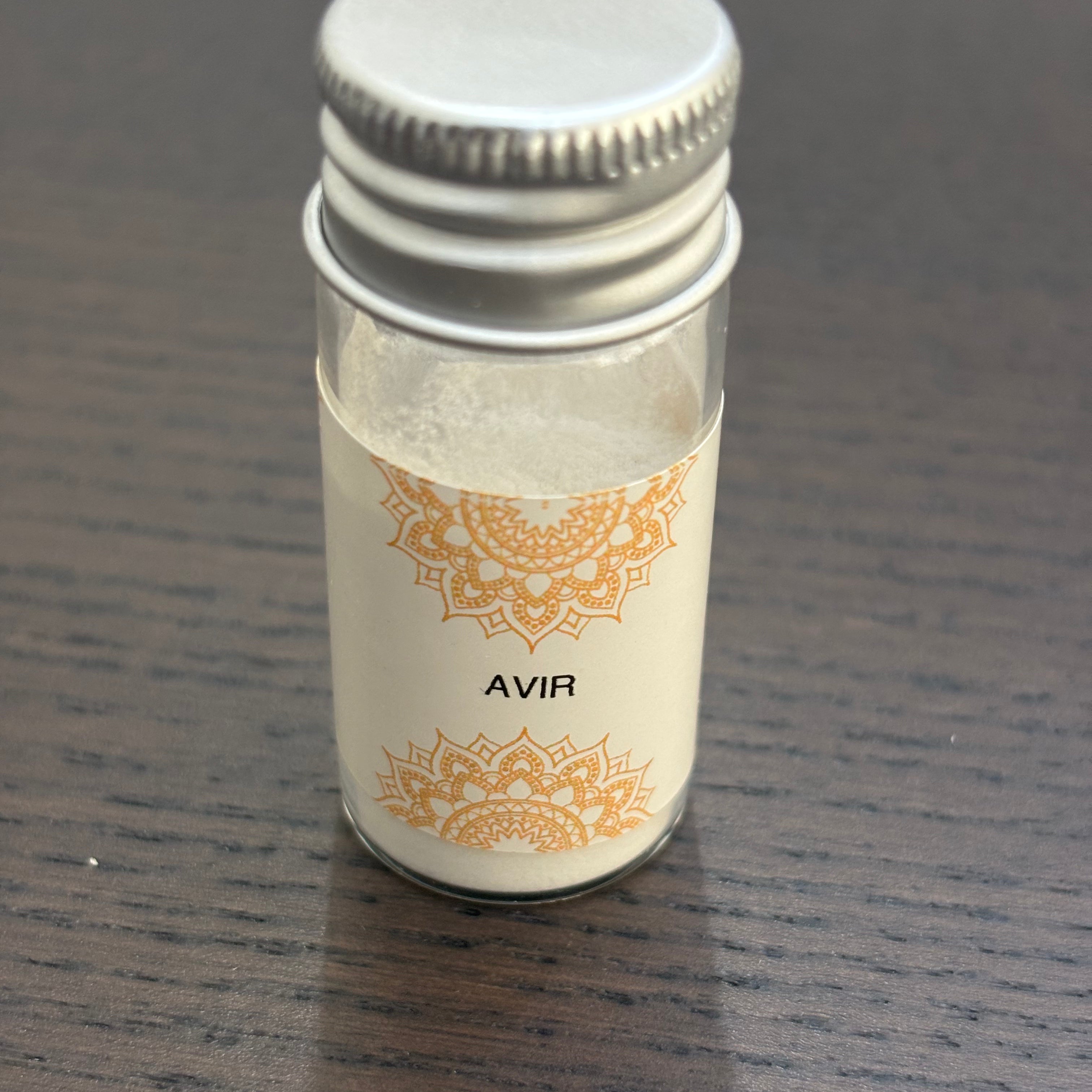 Divine Sansar Avir Powder with a silver cap on a dark wooden surface