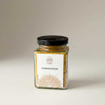 Divine Sansar- Glass jar of Chandan-Kesar powder with a black lid on a neutral background