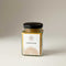 Divine Sansar- Glass jar of Chandan-Kesar powder with a black lid on a neutral background