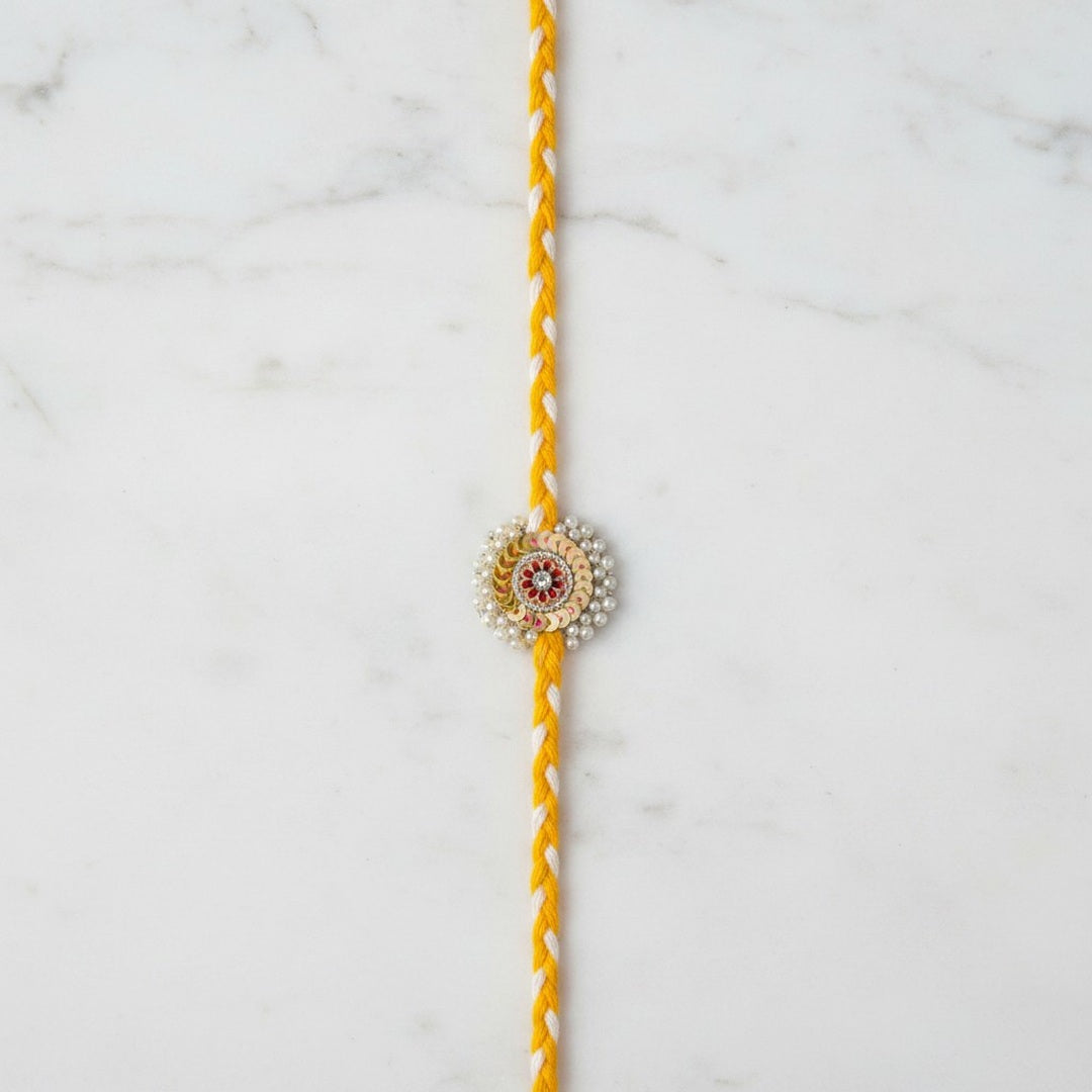 Pearl and gold sequin moti rakhi on marble - Divine Sansar UAE