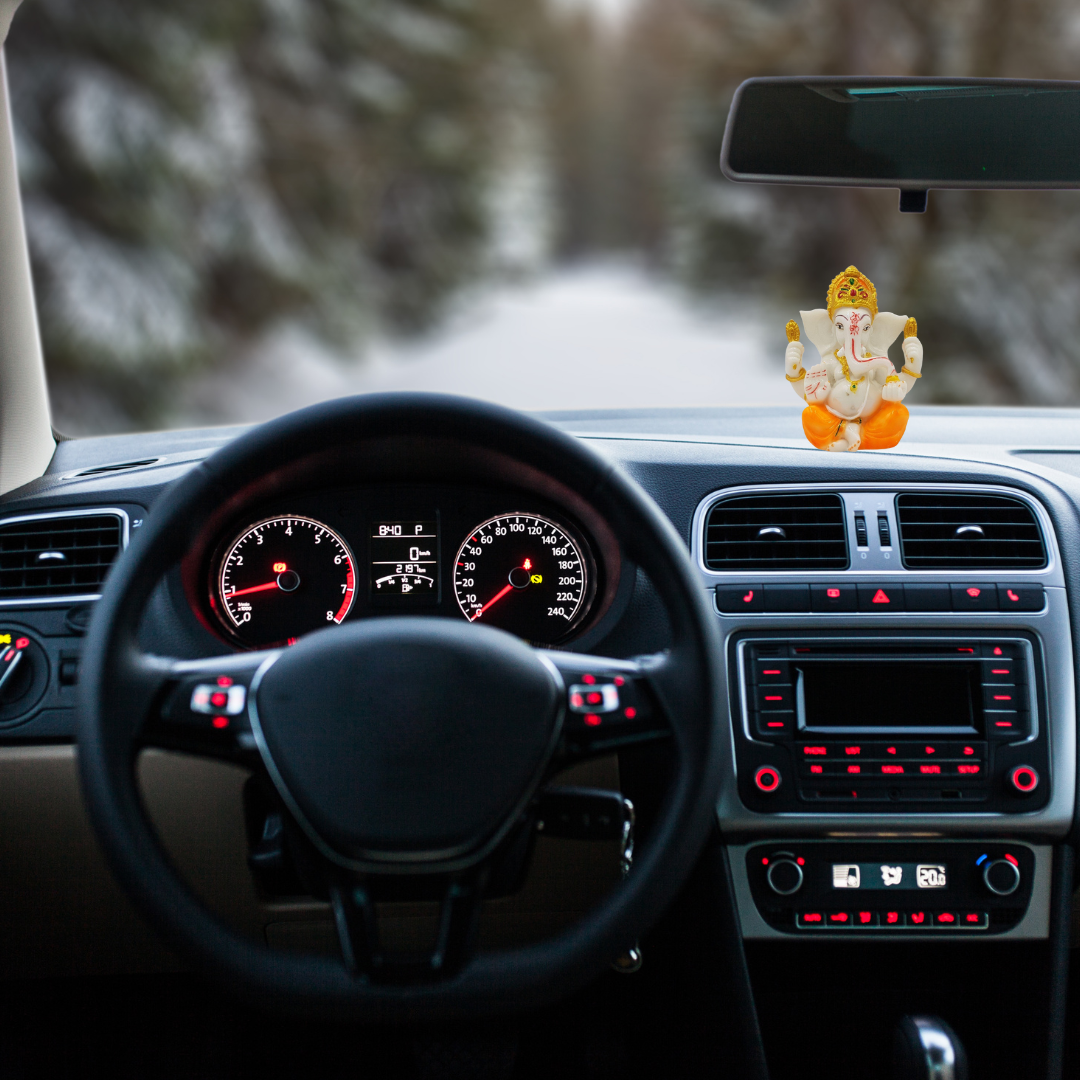 Divine Ganesha Statue White and Orange-Car interior with dashboard lights on, steering wheel, and a Ganesha statue on the dashboard.