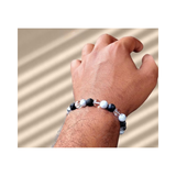 Divine Sansar-Crystal Energy Trinity Bracelet: Howlite · Clear Quartz · Lava-Hand wearing a Crystal Energy Trinity bracelet on a beige background