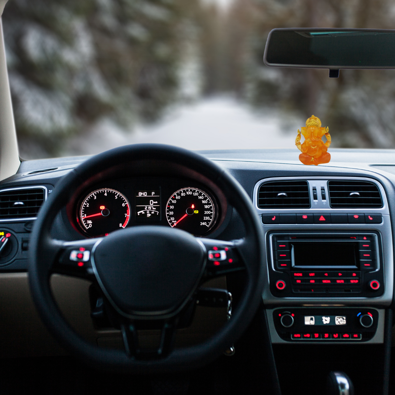 Divine Sansar-Divine Ganesha Statue-Transparent Orange-4 Inches-Car interior with dashboard lights on and a small statue on the dashboard.