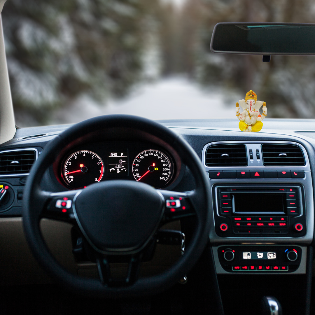 Divine Sansar-Divine Ganesha Statue-White and Orange-4 Inches-Car interior with dashboard and steering wheel, featuring a small statue on the dashboard.