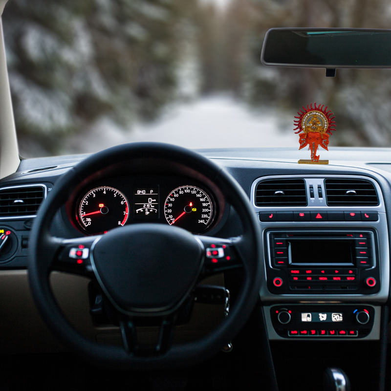 Divine Sansar-Ganpati with Sparkling Stones & Meenakari-Car interior with dashboard lights on and a Ganpati with Sparkling Stones & Meenakari on the dashboard.