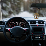 Divine Sansar-Golden Khanda Sahib Idol with Sparkling Stones-Car interior with dashboard and steering wheel, blurred road in the background