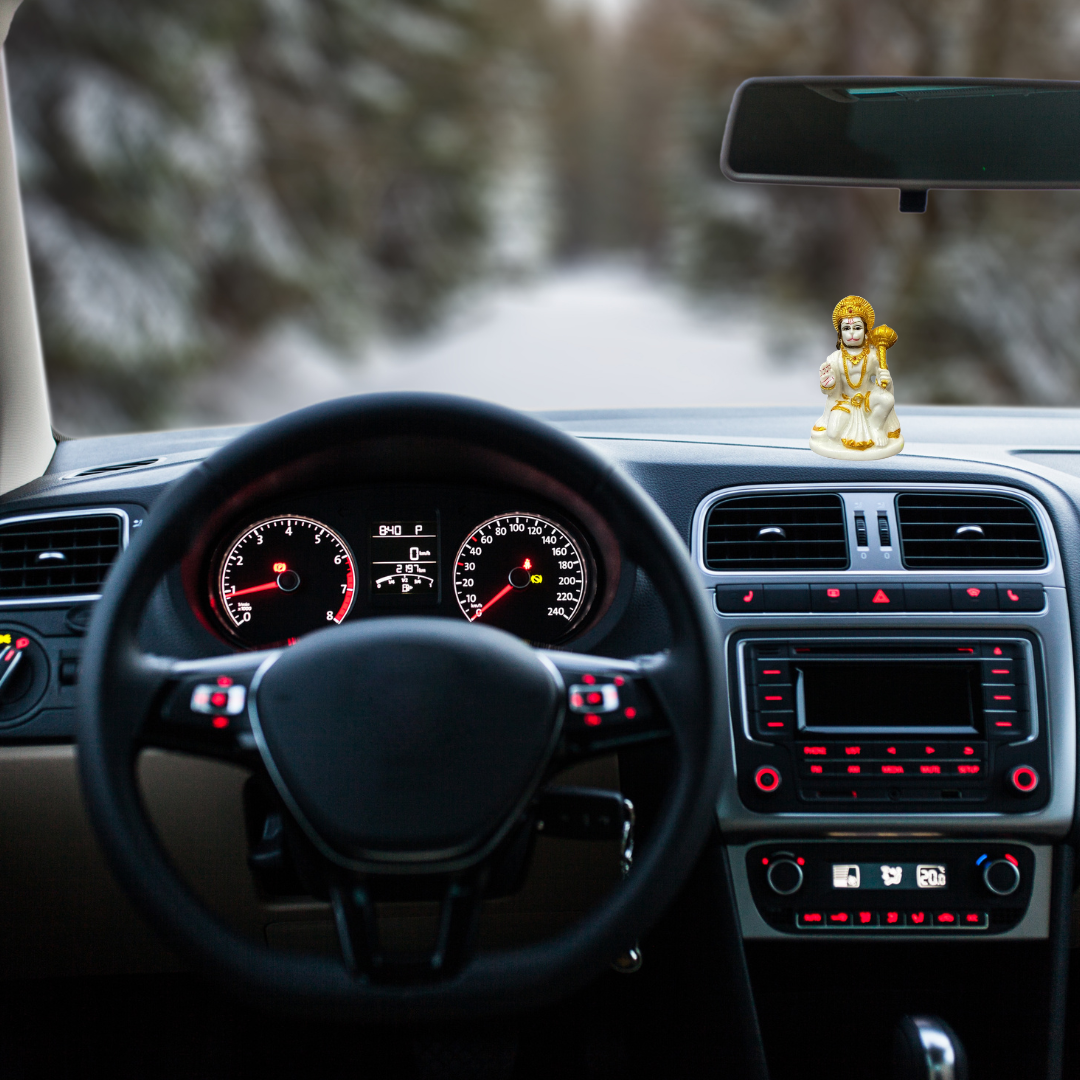 Divine Sansar-Hanumanji Statue in White & Gold-Car interior with dashboard lights on, steering wheel, and Hanumanji Statue in White & Gold on the dashboard.