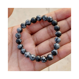 Divine Sansar-InnerPeace Bracelet-Snowflake Obsidian bracelet on a hand against a neutral background