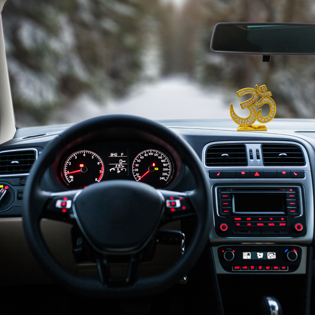 Divine Sansar-Premium Crystal OM Statue - Gold & Silver variants-Car interior with a steering wheel and dashboard, featuring Premium Crystal OM Statue on the dashboard.