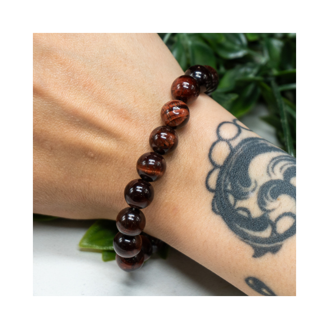 Divine Sansar-Red Tiger Eye Bracelet on a wrist with a tattoo, against a white background