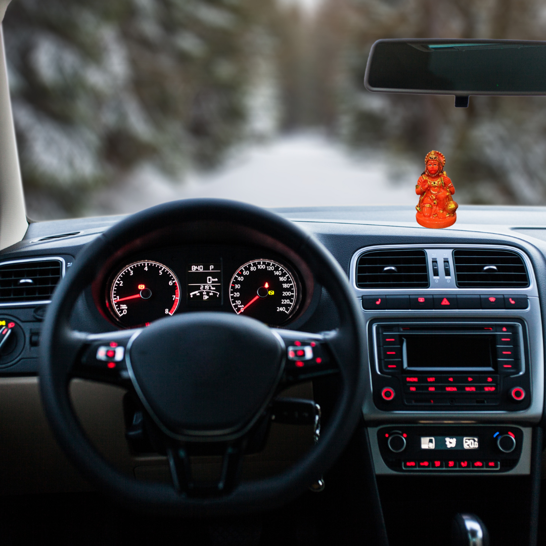 Divine Sansar-Saffron Hanumanji Statue-Car interior with dashboard lights on and a Saffron Hanumanji Statue on the dashboard.