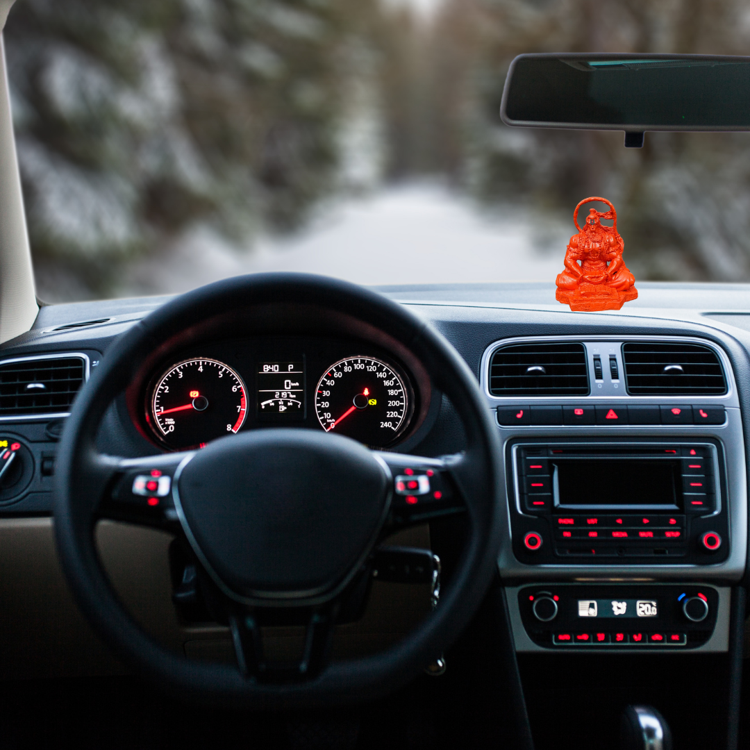 Divine Sansar-Saffron Hanumanji Statue-Car interior with dashboard lights on, steering wheel, and Saffron Hanumanji Statue on the dashboard.