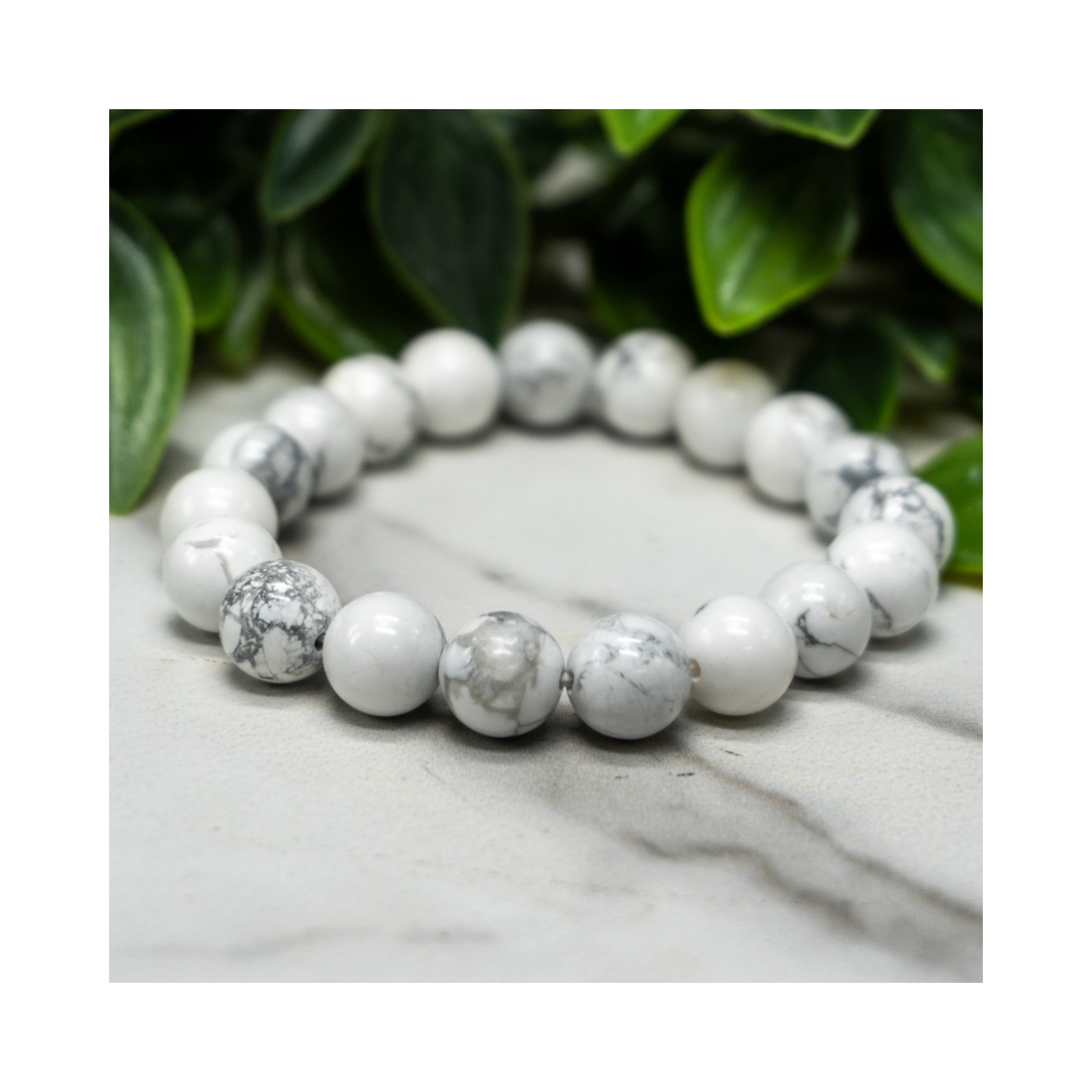 Divine Sansar-Soothing Bracelet: Howlite bracelet on a marble surface with green leaves in the background