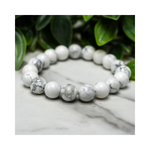 Divine Sansar-Soothing Bracelet: Howlite bracelet on a marble surface with green leaves in the background