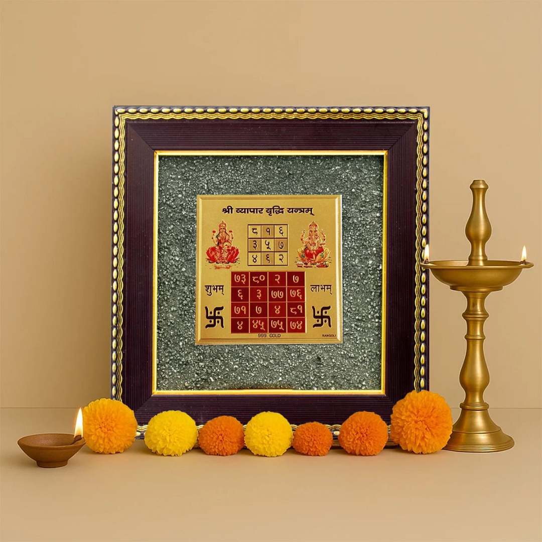 Divine Sansar Pyrite Stone Frame with Vyapar Vridhhi Yantra on a beige background, accompanied by colorful flowers and a brass lamp.