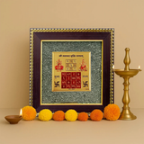 Divine Sansar Pyrite Stone Frame with Vyapar Vridhhi Yantra on a beige background, accompanied by colorful flowers and a brass lamp.