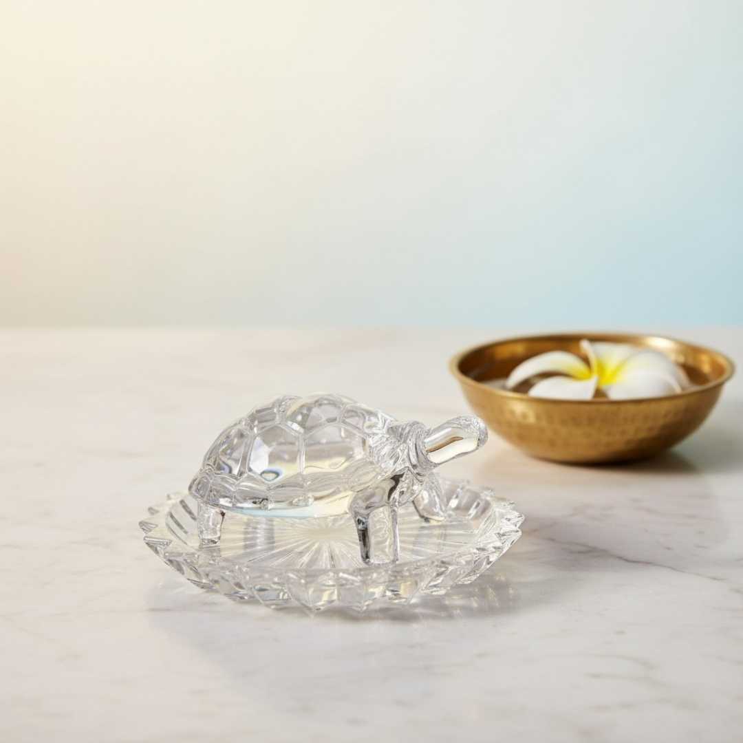 Divine Sansar Wish Fulfilling Crystal Turtle with water bowl-Wish Fulfilling Crystal Turtle on a marble surface, next to a gold bowl with flowers.