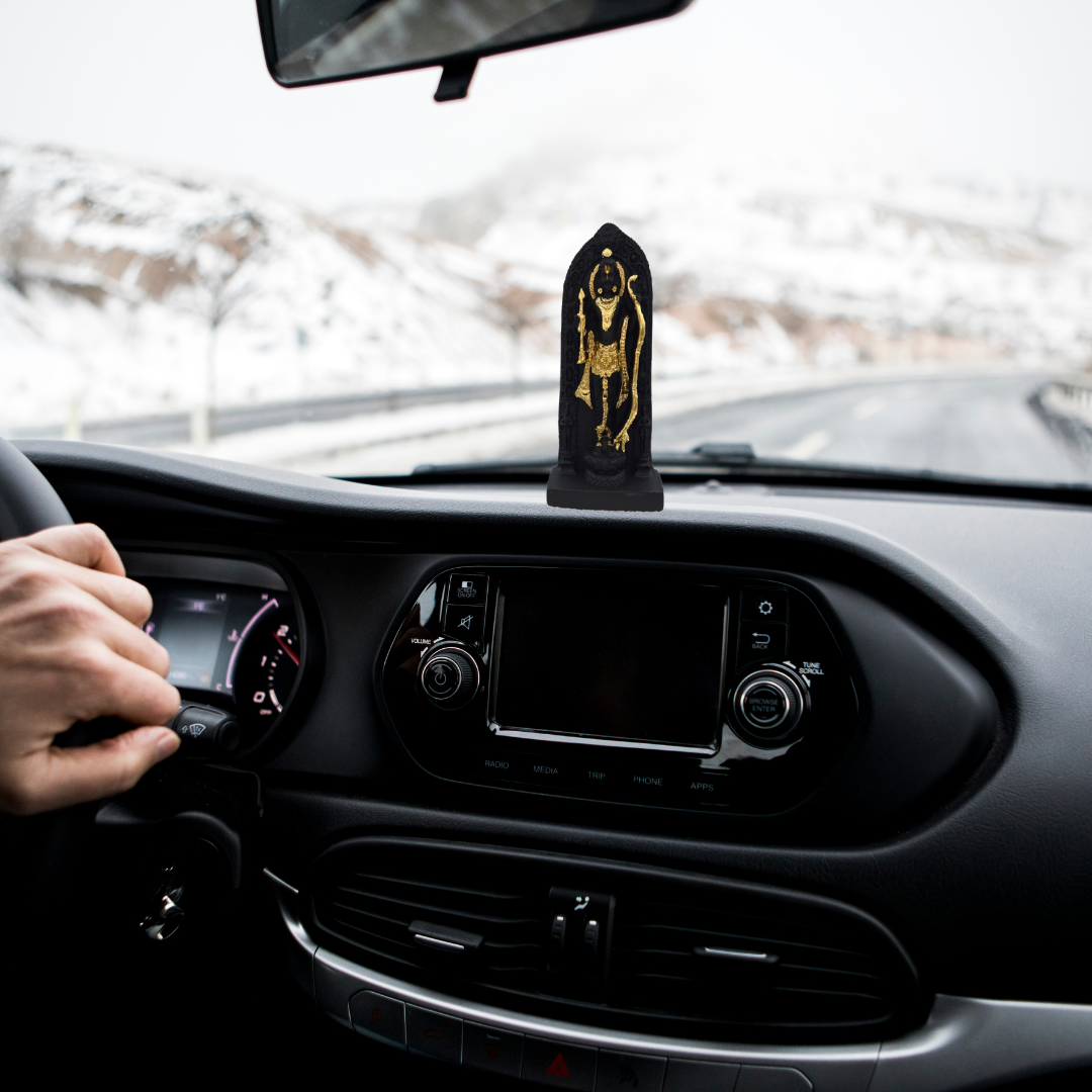 Divine Sansar-Divine Shri Ram Lala Idol-Car dashboard with a Ram Lala statue and a hand on the steering wheel, snow outside.