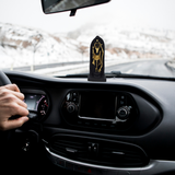 Divine Sansar-Divine Shri Ram Lala Idol-Car dashboard with a Ram Lala statue and a hand on the steering wheel, snow outside.