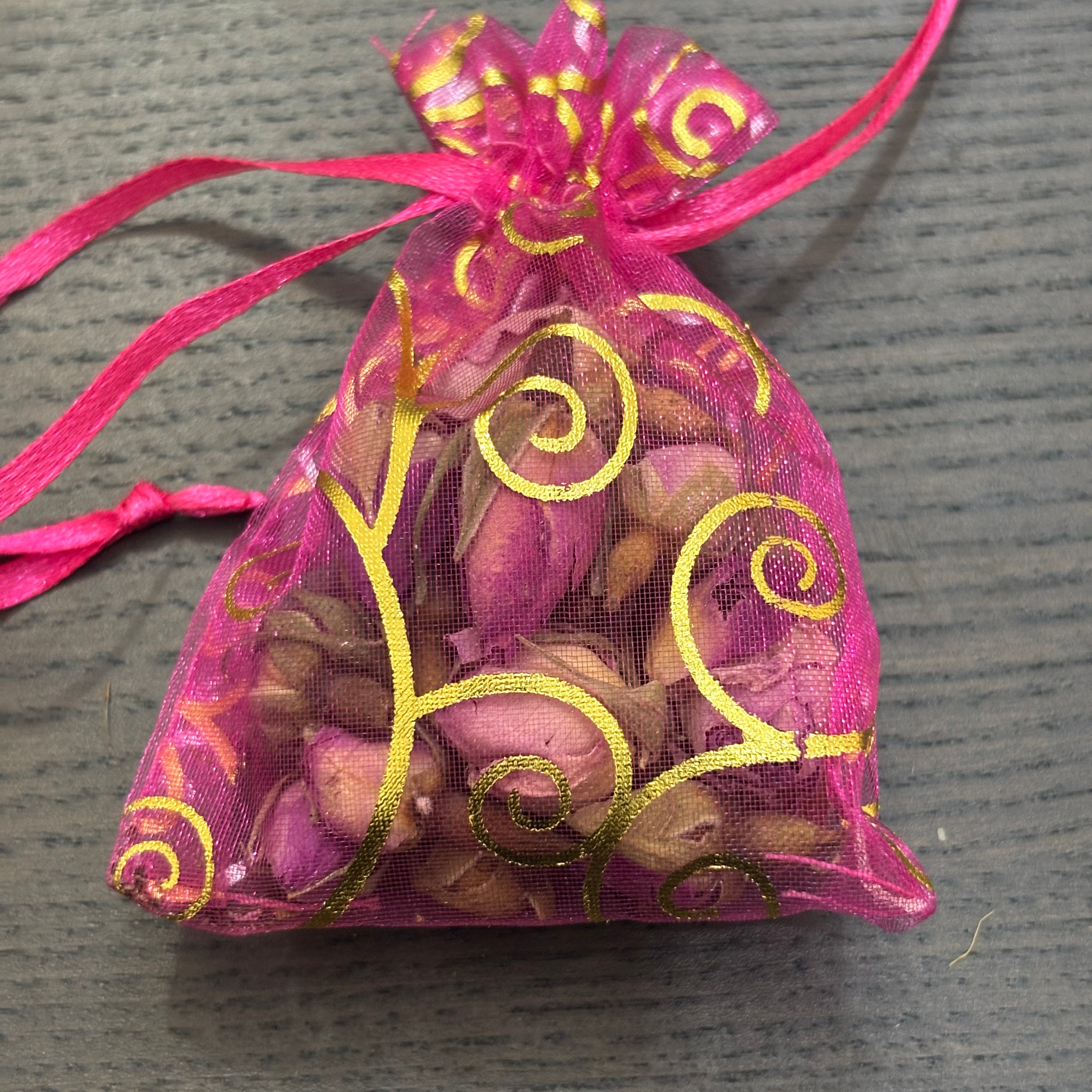 Divine Sansar- a small, pink organza gift pouch filled with dried rose buds.