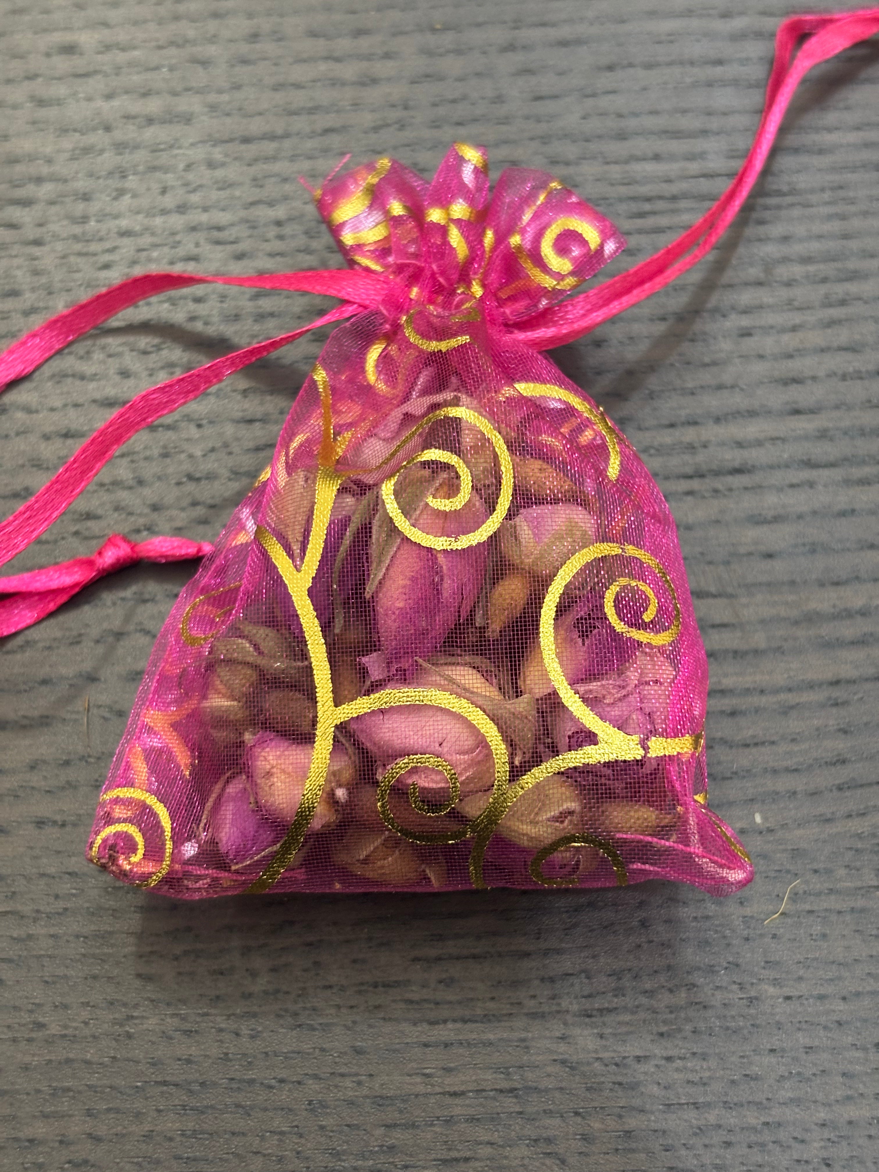 Divine Sansar- a small, pink organza gift pouch filled with dried rose buds.