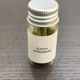 Divine Sansar Elaichi (Cardamom) bottle  with metal lid containing cardamom on a gray surface