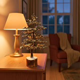 Geniune Pyrite Stone Tree of Life on a wooden table with a lamp and chair in a cozy room.