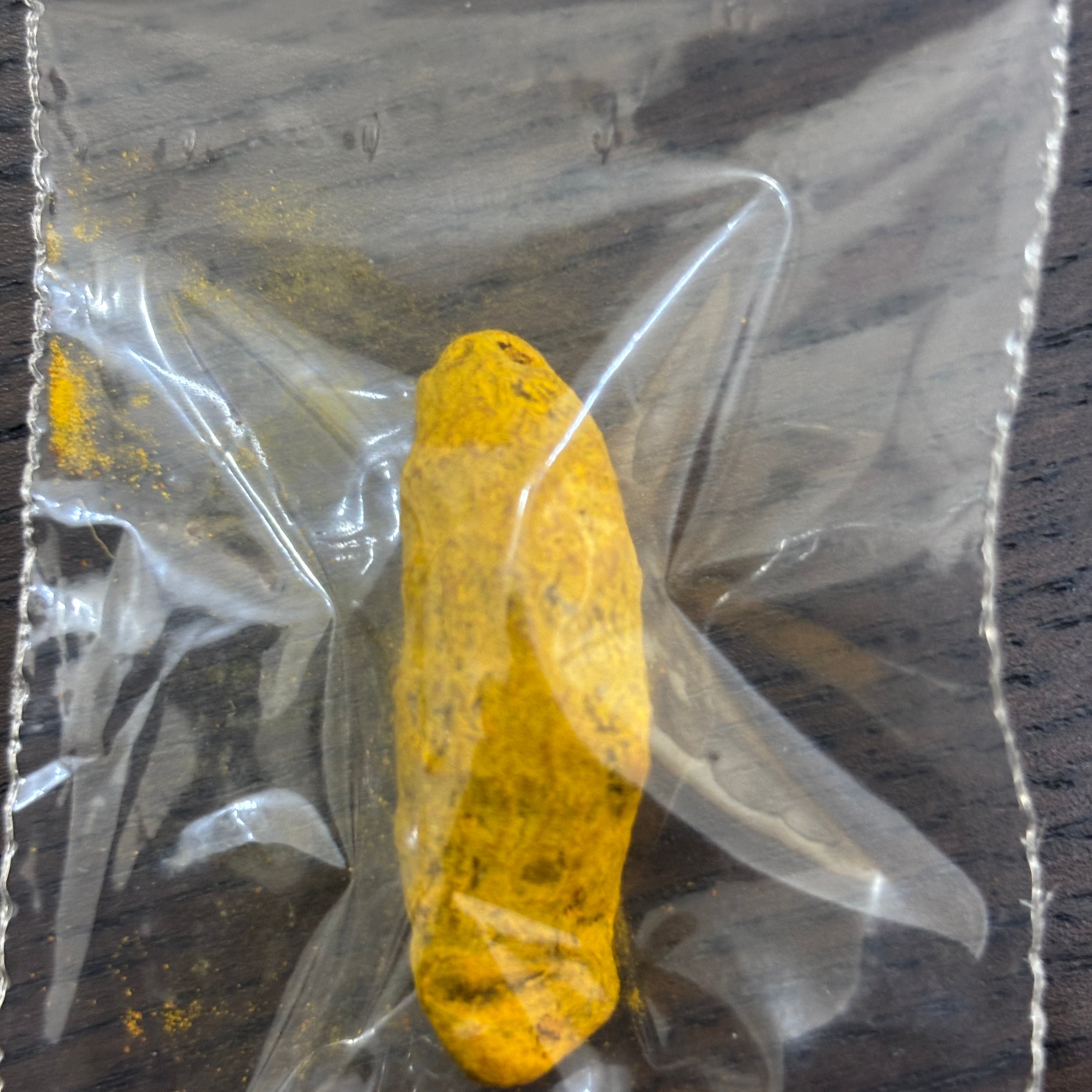 Divine Sansar Haldi Sabut (Turmeric Whole) in a clear plastic bag on a wooden surface