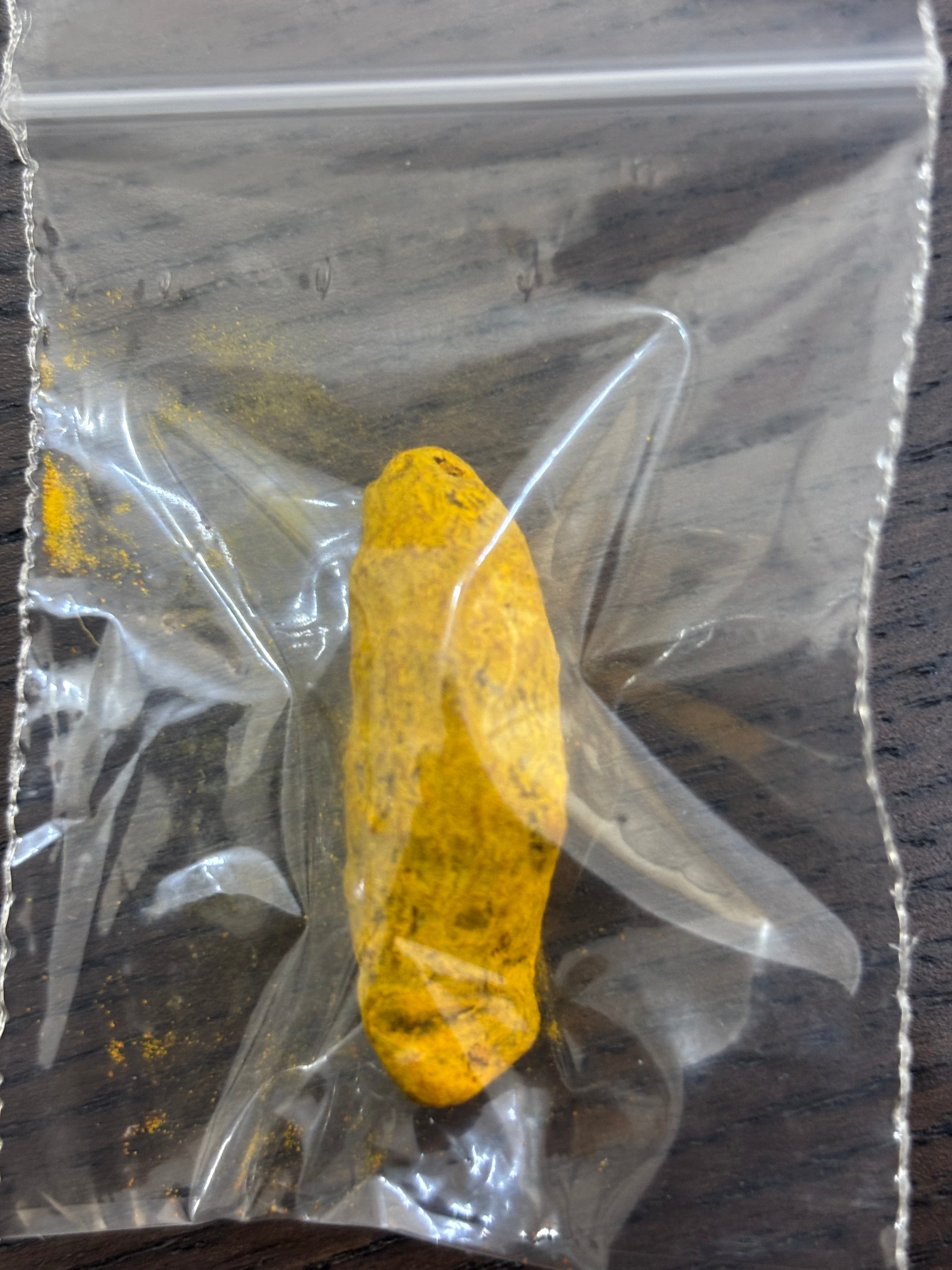 Divine Sansar Haldi Sabut (Turmeric Whole) in a clear plastic bag on a wooden surface