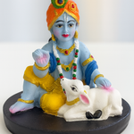 Divine Sansar-Hand-Painted Baby Krishna with Calf Idol on a black base against a white background