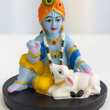 Divine Sansar-Hand-Painted Baby Krishna with Calf Idol on a black base against a white background