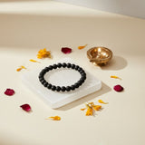 Karungali ebony bracelet resting on a selenite charging plate - Divine Sansar
