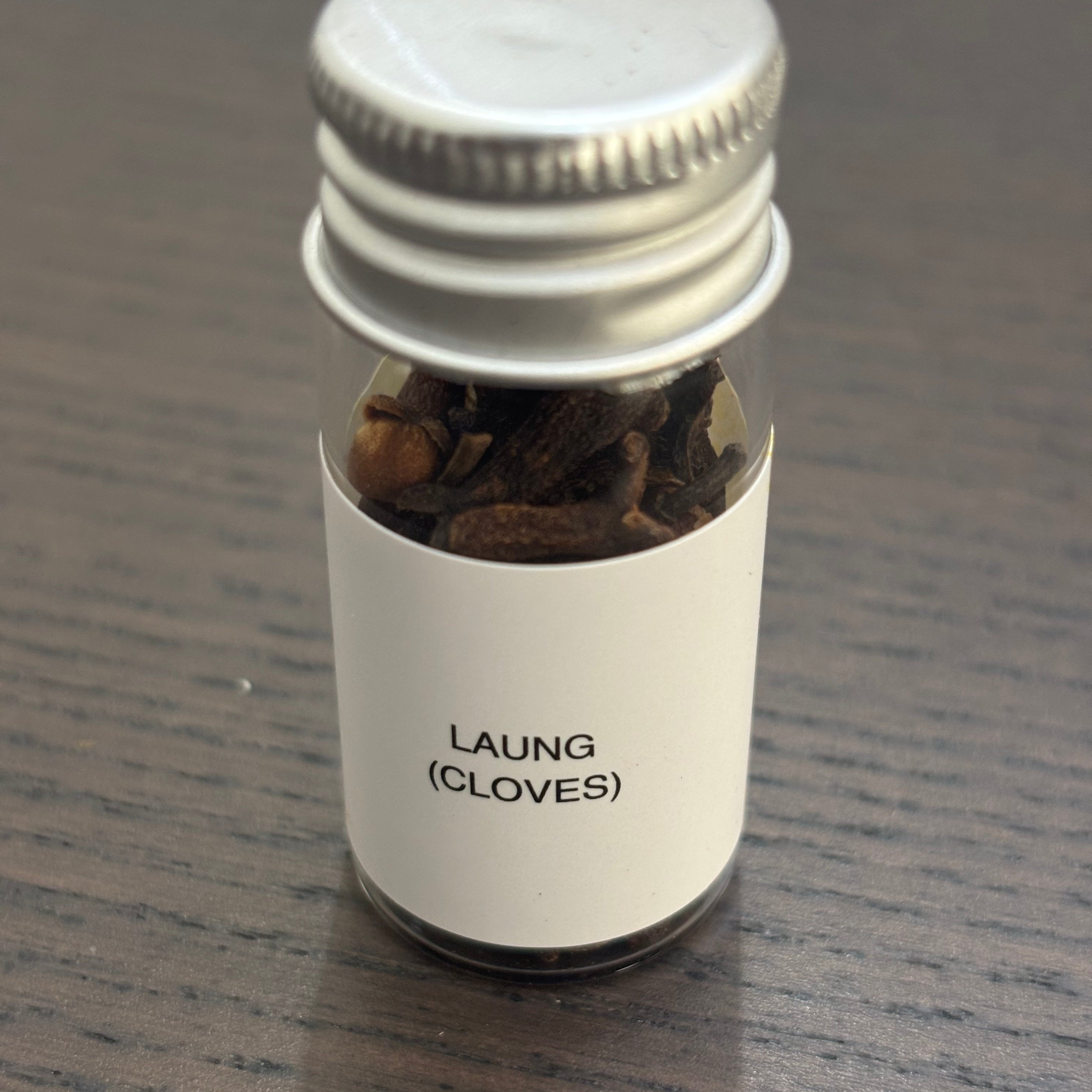 Divine Sansar Laung (cloves) bottle with a metal cap on a wooden surface.