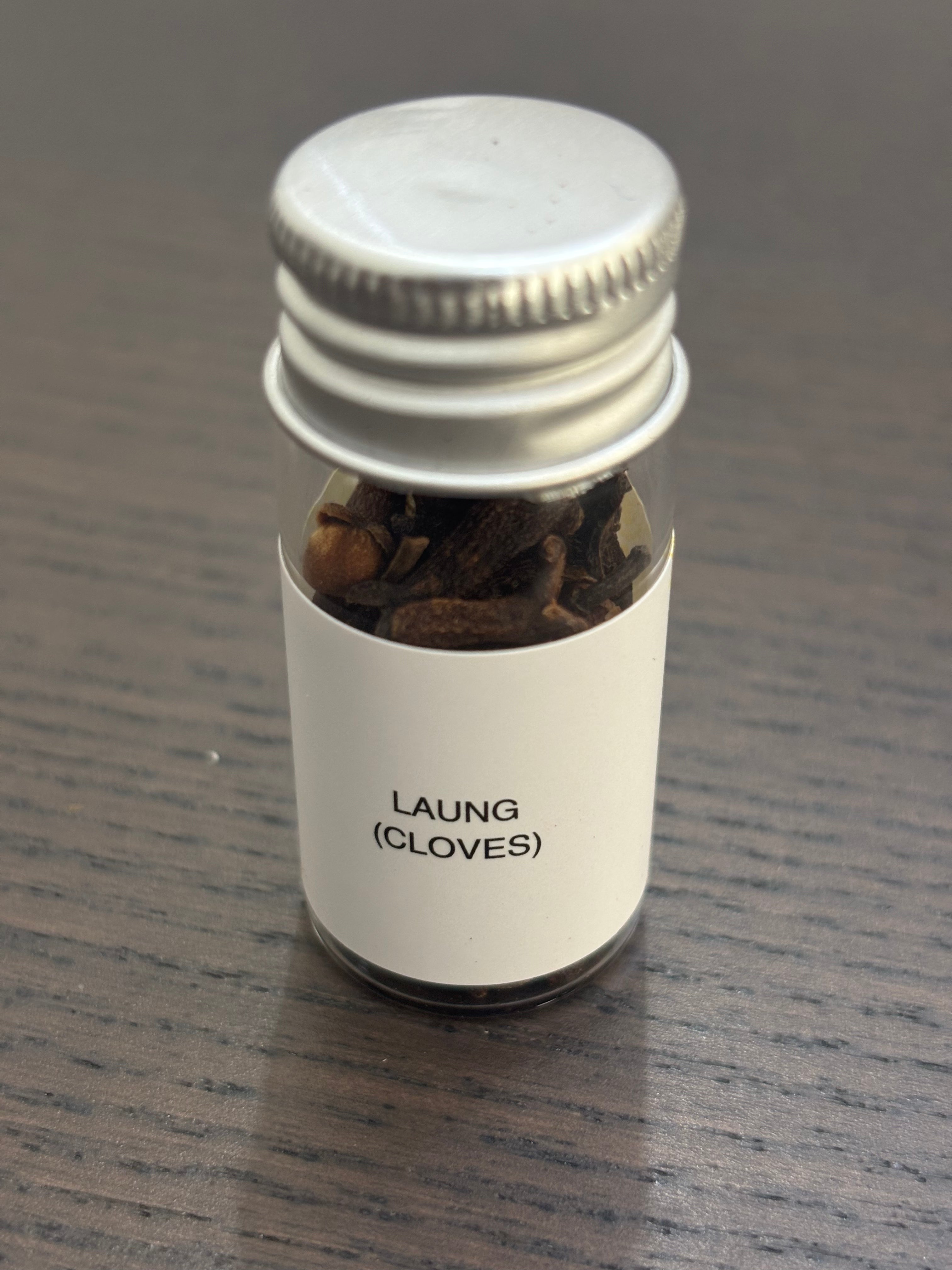 Divine Sansar Laung (cloves) bottle with a metal cap on a wooden surface.