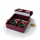 Laxmi Charan gift box open with the lid alongside, its foam pad die-cut with two round seats for the covers, and the terracotta pair seated in the maroon box, Divine Sansar