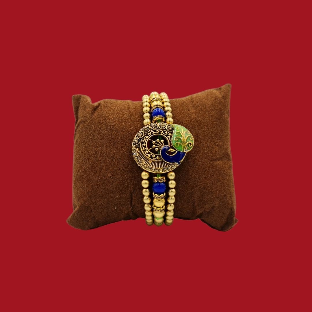 Divine Sansar Meenakari Peacock Rakhi Design 1 brown pillow against a red background