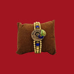 Divine Sansar Meenakari Peacock Rakhi Design 1 brown pillow against a red background