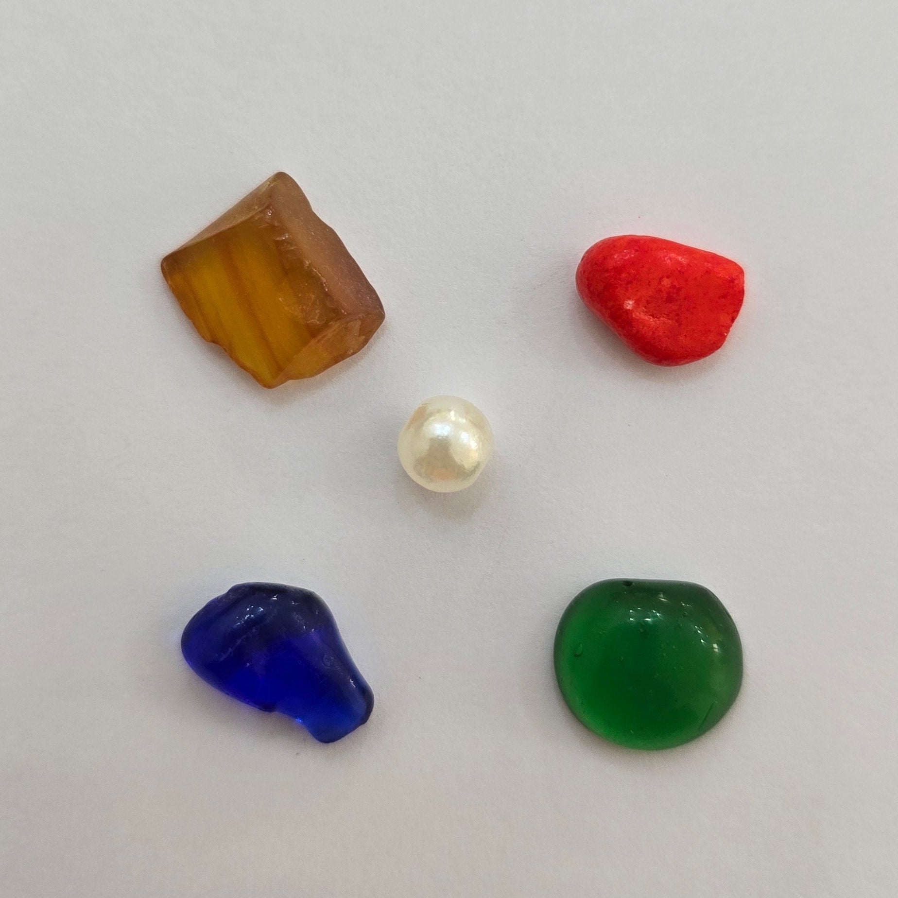 Divine Sansar-Five colored stones on a light gray background