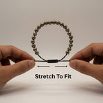 Divine Sansar-Pyrite Braided Bracelet stretch to fit-Hands stretching a Pyrite Braided Bracelet to fit on a wrist against a neutral background