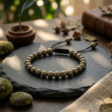 Divine Sansar-Pyrite Braided Money magnet ambiant-pyrite braided bracelet on a dark surface