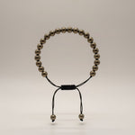 Divine Sansar Pyrite Braided front- Beaded bracelet with black cord on a light gray background