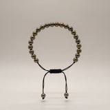 Divine Sansar Pyrite Braided front- Beaded bracelet with black cord on a light gray background