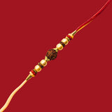 Divine Sansar Rudraksha Rakhi 1 with gold and red beads on a red background