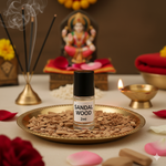 Divine Sansar-Sandalwood Attar bottle 2ml on a tray with incense sticks, flowers, and a statue in the background.