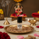 Divine Sansar-Sandalwood Attar bottle 2ml on a tray with incense sticks, flowers, and a statue in the background.